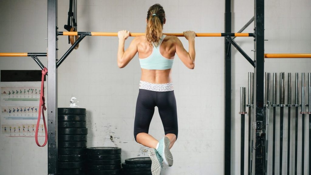 Strong woman performing a pull-up exercise with determination.”