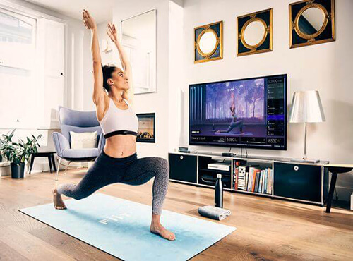 A woman practicing yoga on a mat in her living room, surrounded by a calm and cozy environment."